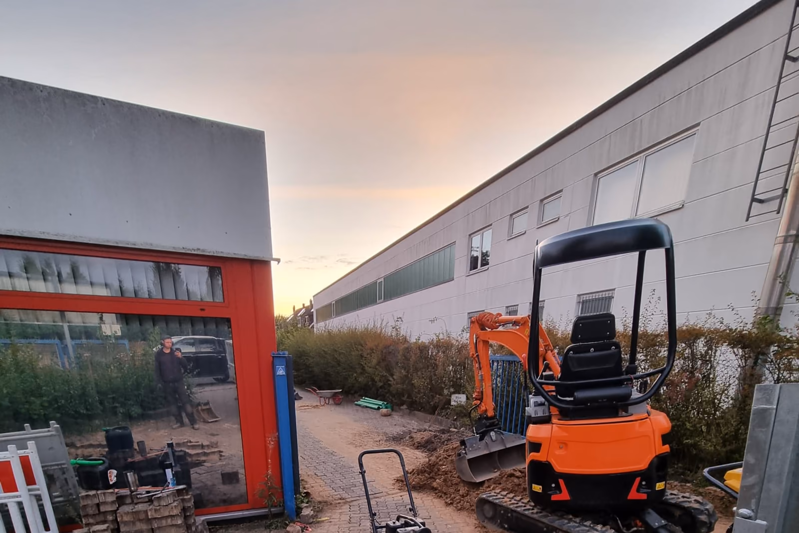 Minibagger auf einem Gewerbehof im Abendlicht nach abgeschlossenen Erdarbeiten